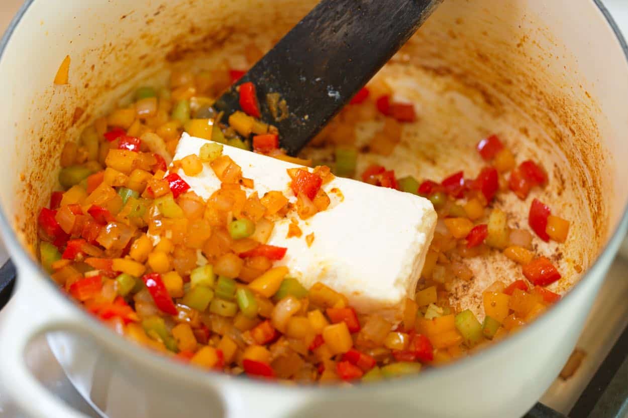 Stirring cream cheese into the vegetables to make the chili creamy