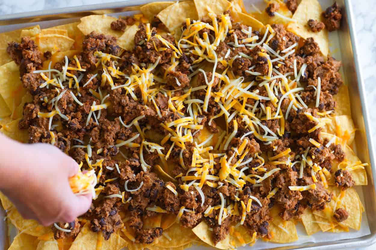 Adding cheese to nachos before baking