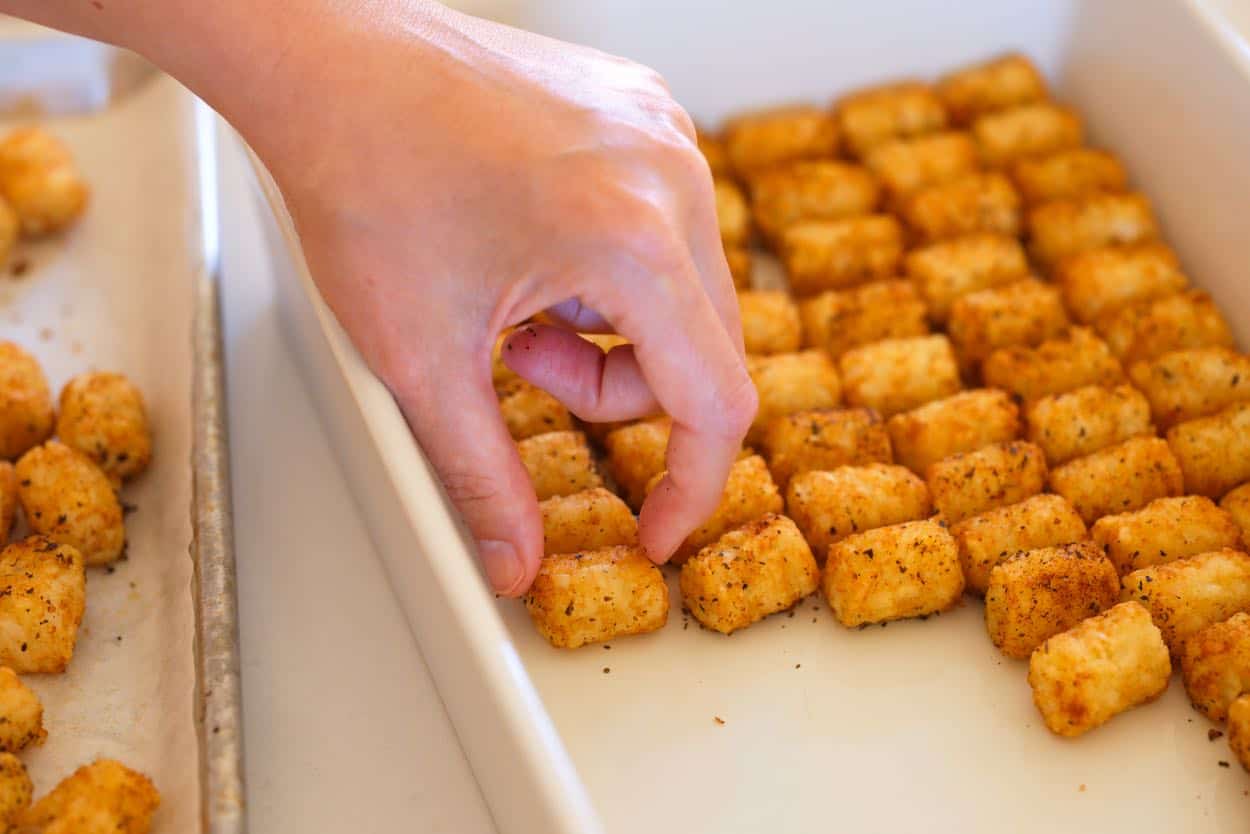 Lining the bottom of a baking dish with tater tots for a breakfast casserole