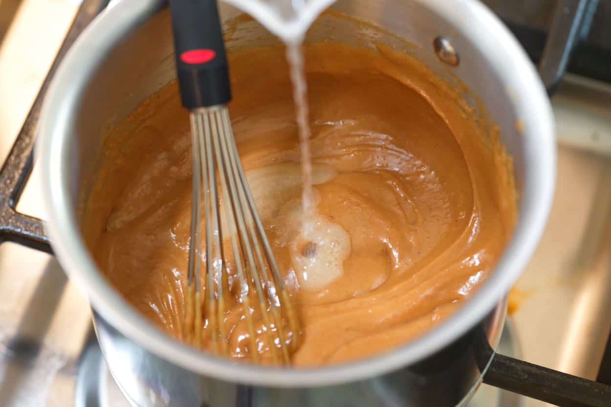 maišant vandenį, kad emulsifikuotų padažas iš žemės riešutų