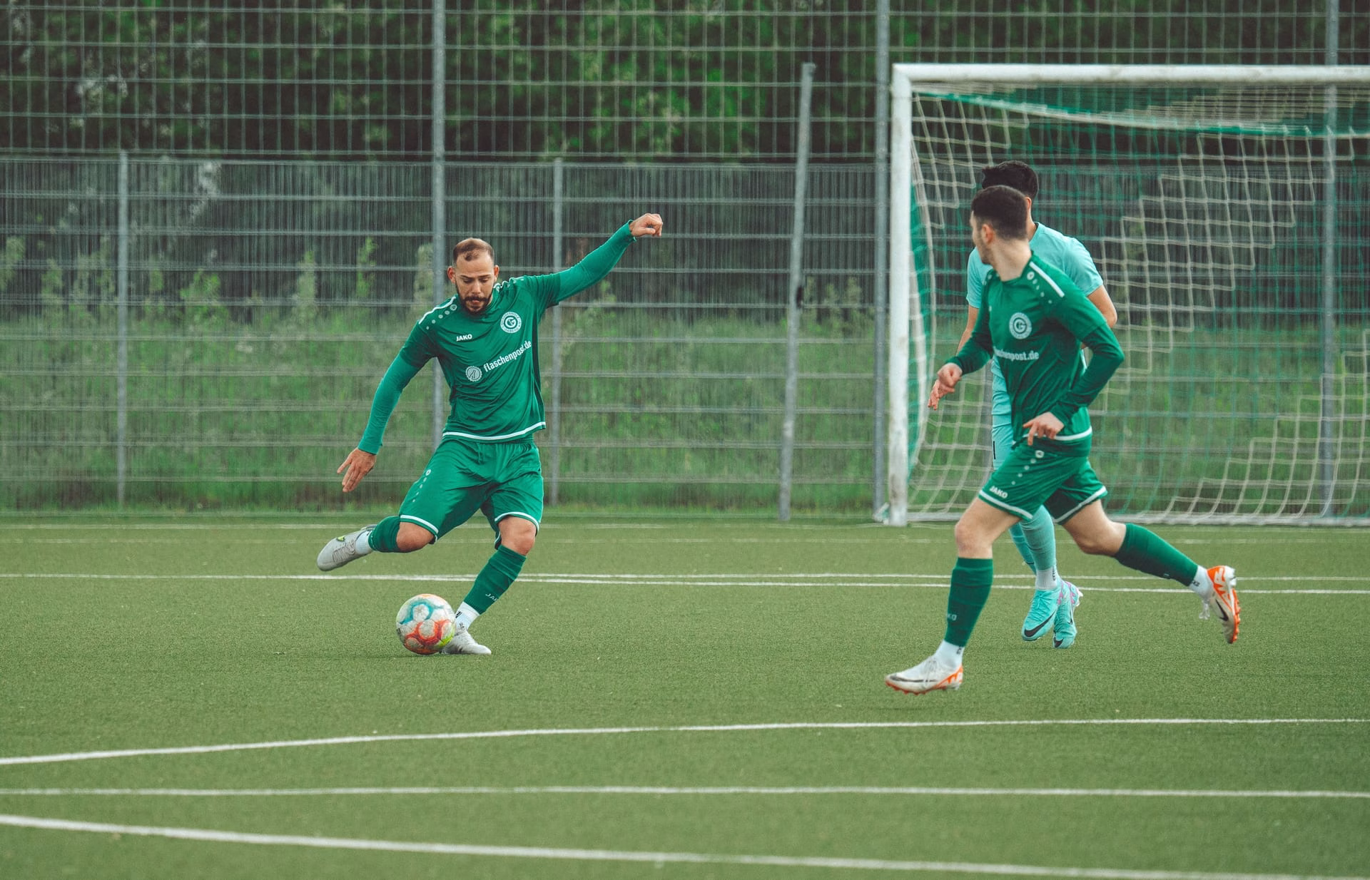 Players in green uniforms engage in a dynamic soccer match on a grassy field.