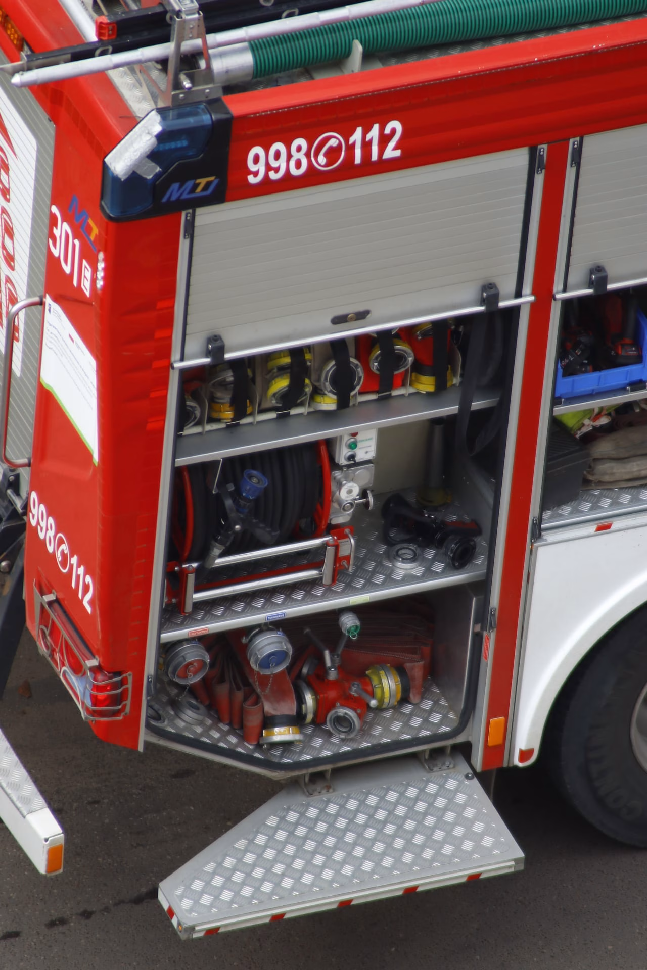 Detailed view of firetruck equipment with hoses and tools, highlighting readiness.