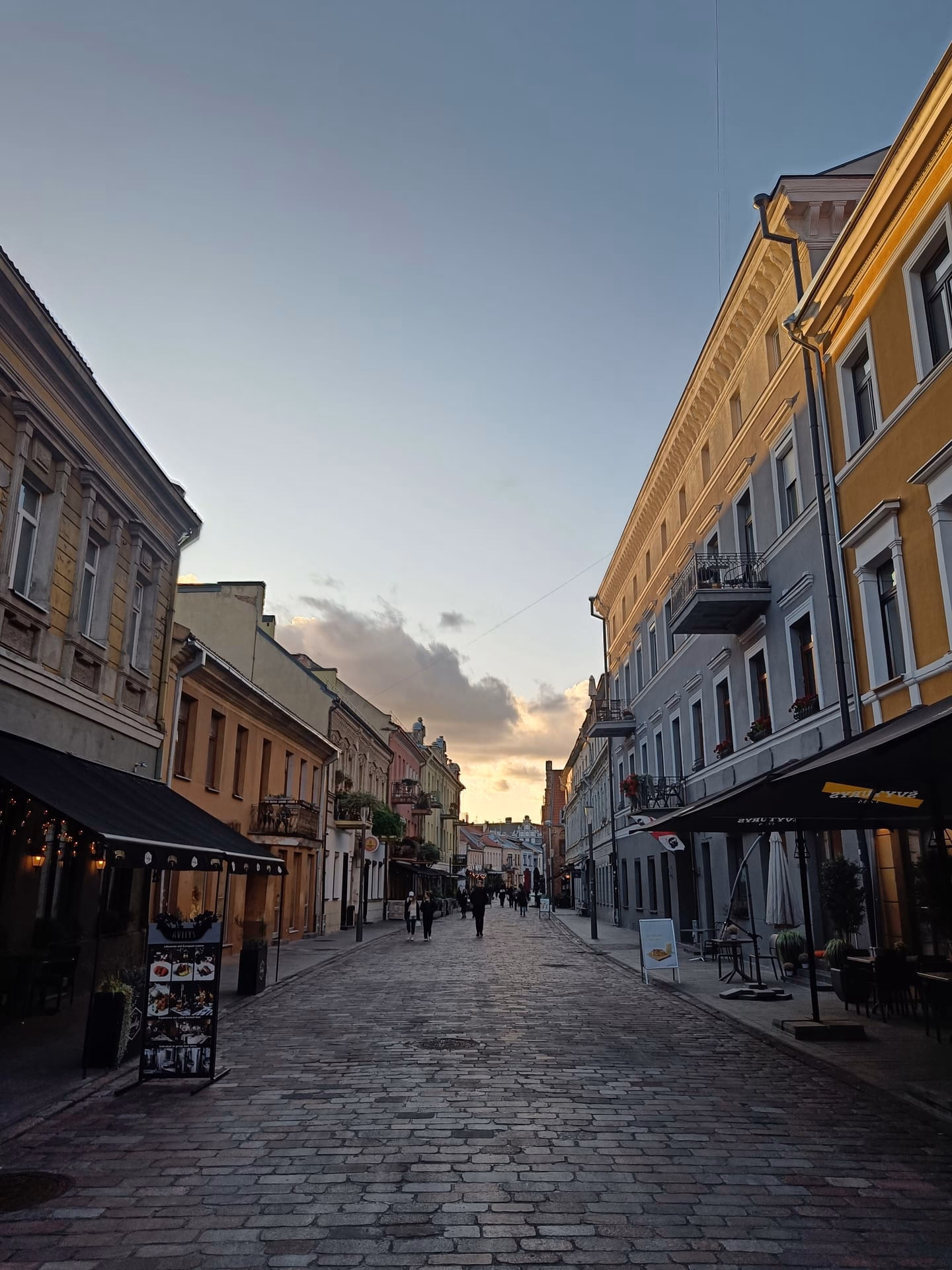 Beautiful cobblestone street in Old Town Kaunas, Lithuania during sunset showcasing vibrant architecture.