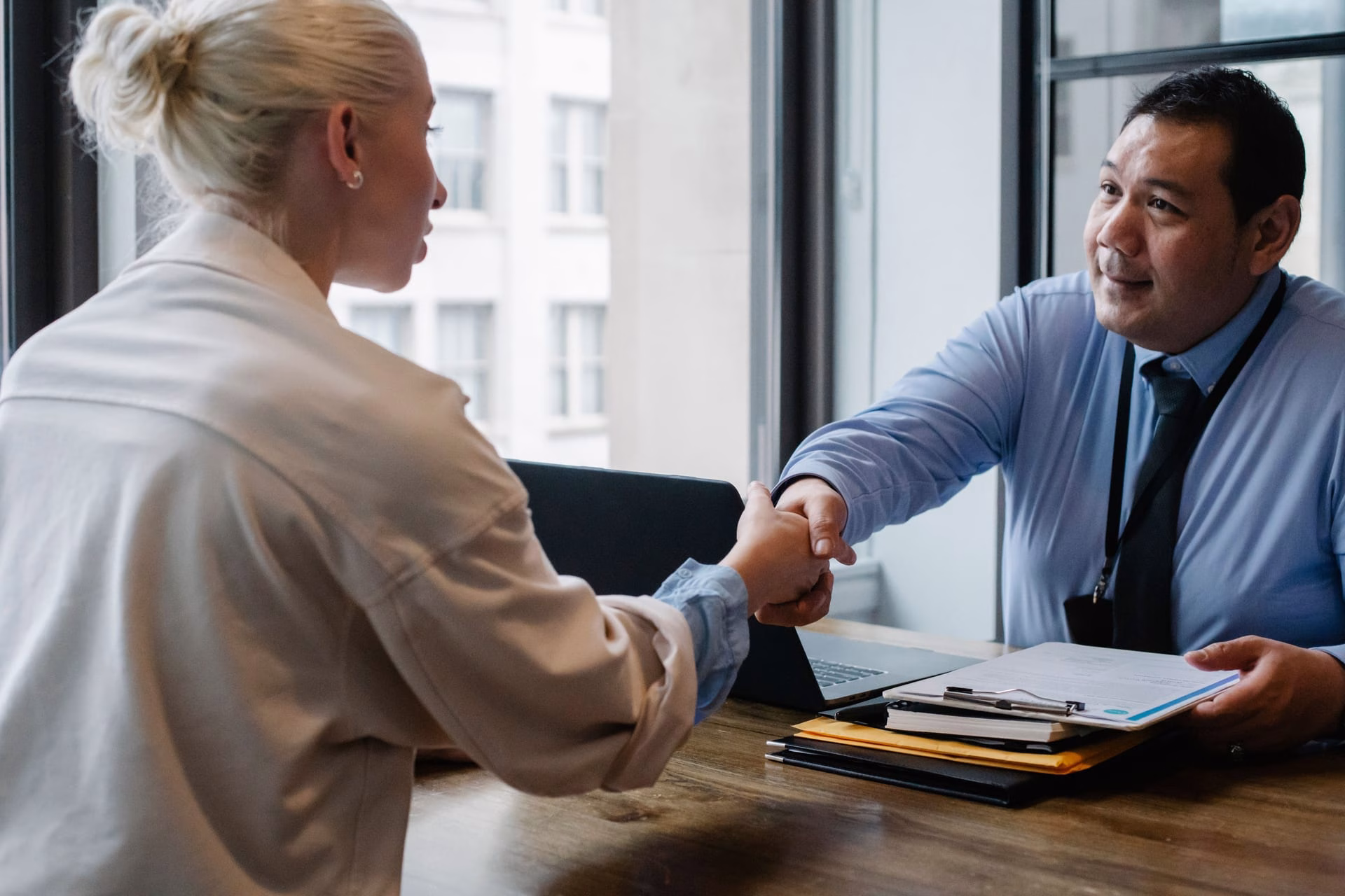 Ethnic male entrepreneur shaking hand of female candidate during job interview in business company