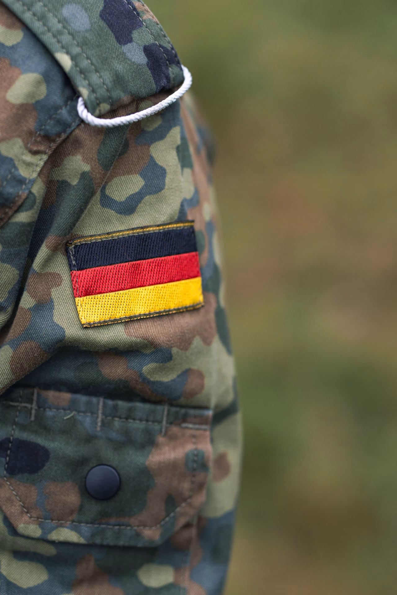 Closeup of German military camouflage uniform with flag patch, symbolizing national pride.