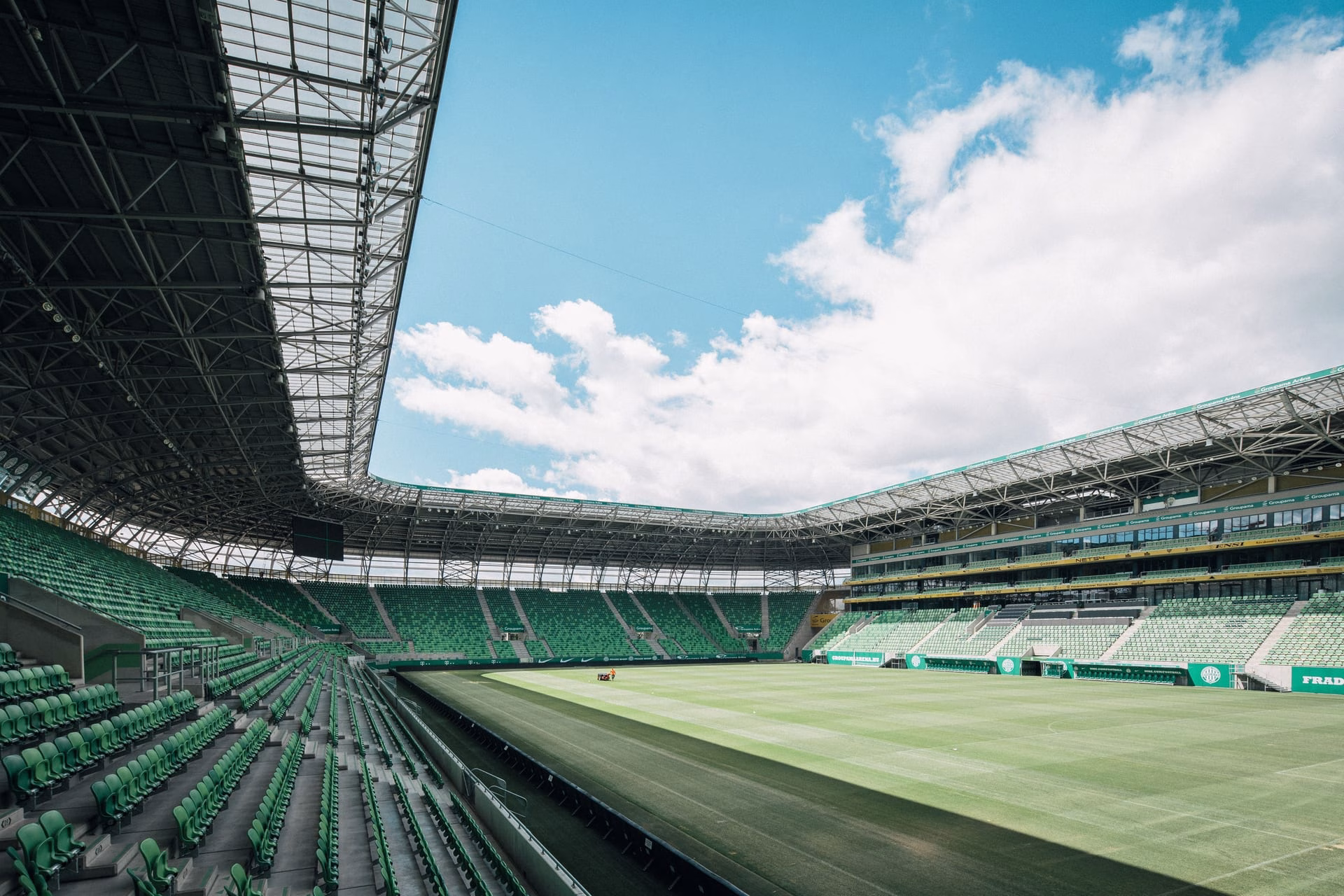View of a modern stadium in Budapest, Hungary, showcasing green seats and a vast open sky.