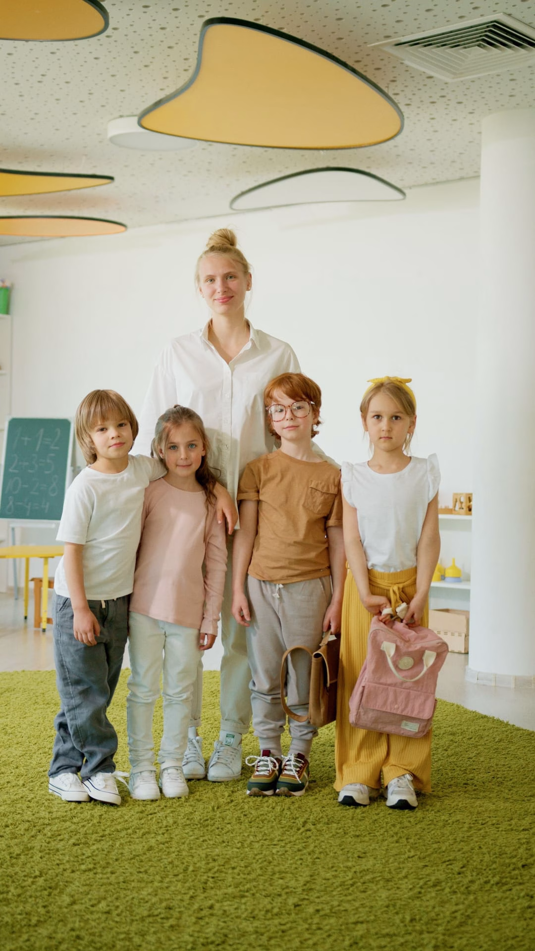 A cheerful teacher with a group of children in a brightly lit classroom, fostering learning.