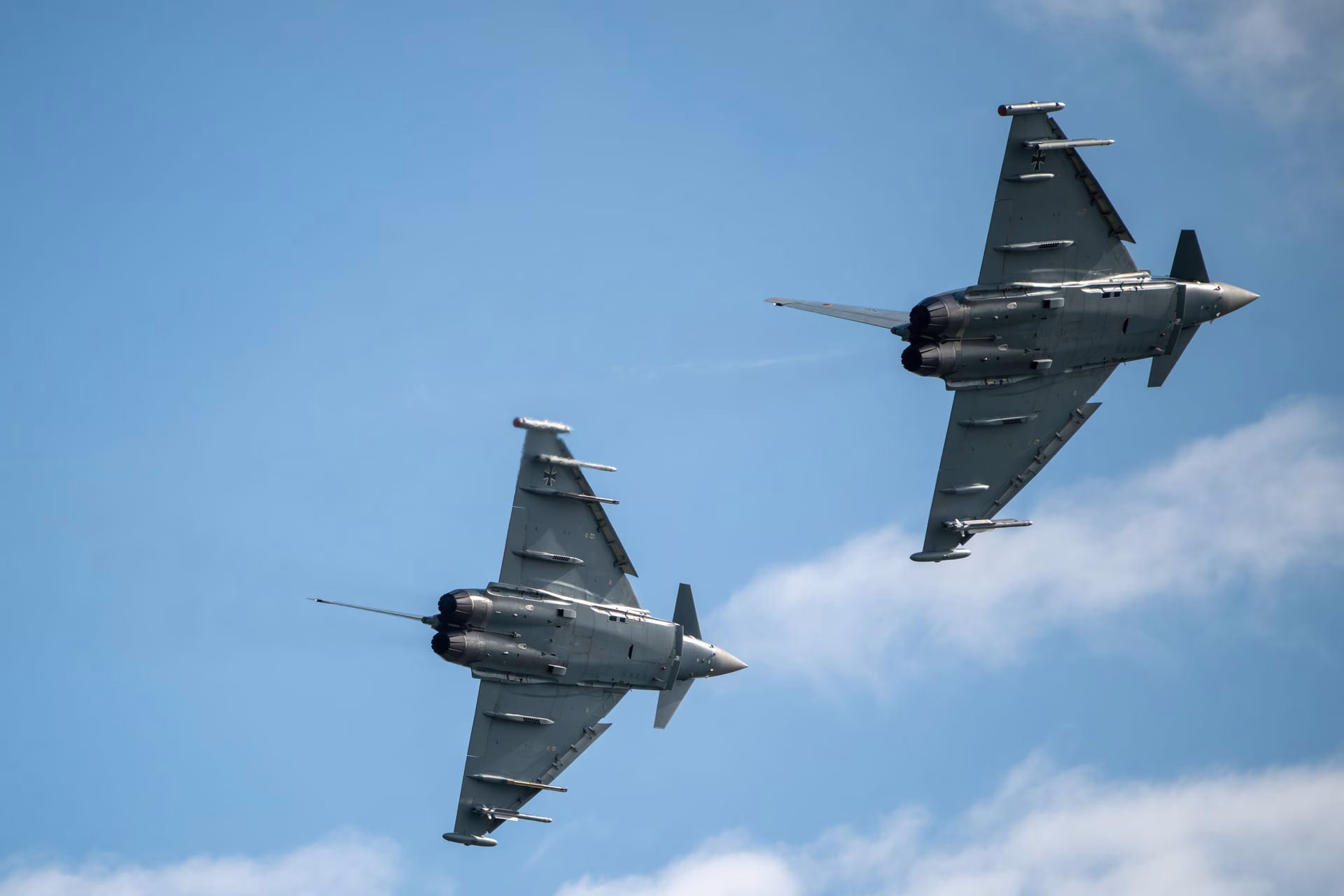Two Eurofighter Typhoons soaring in formation against a clear blue sky, showcasing military aviation prowess.