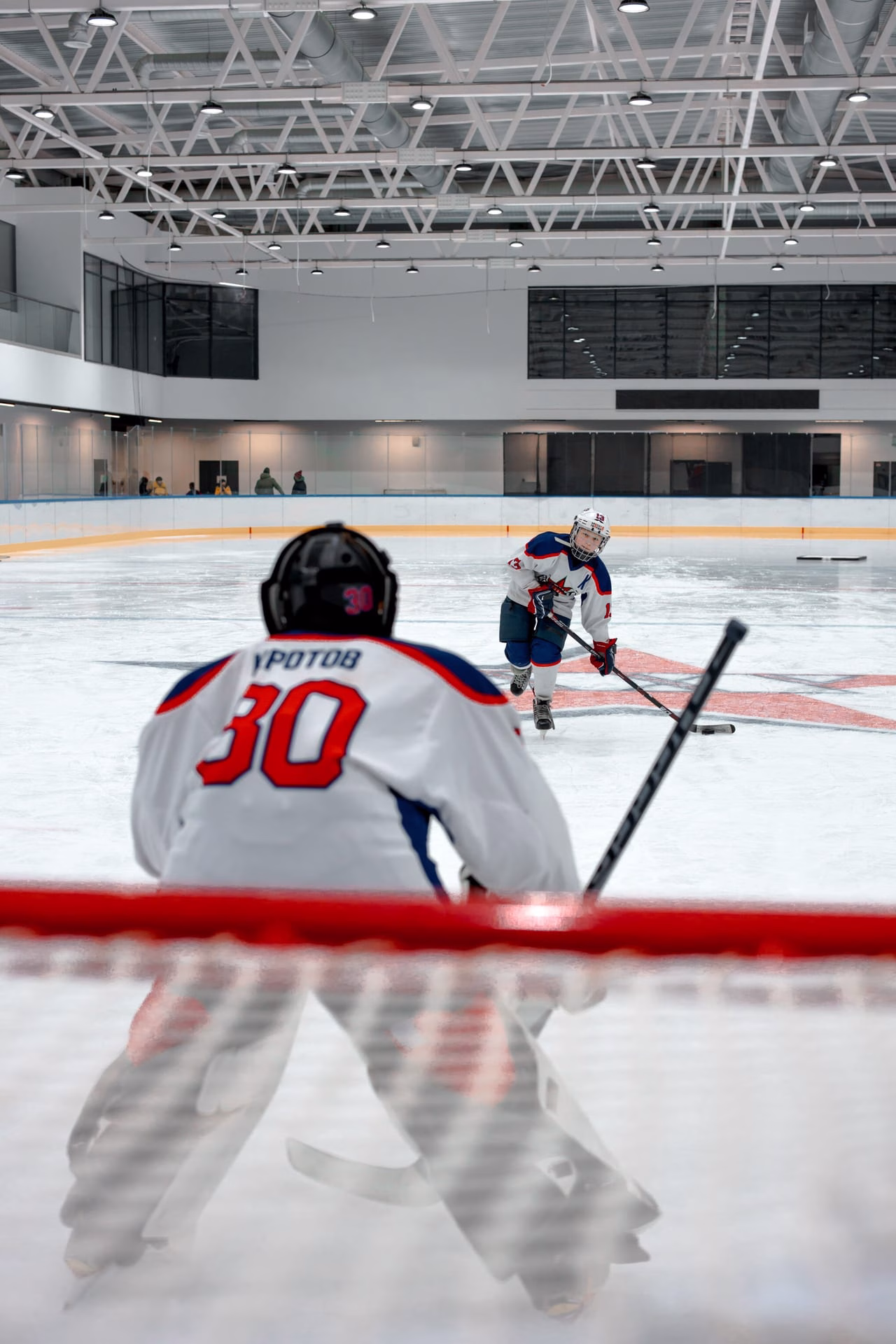 Dynamic ice hockey game indoors with a focus on the goalie and player interaction.