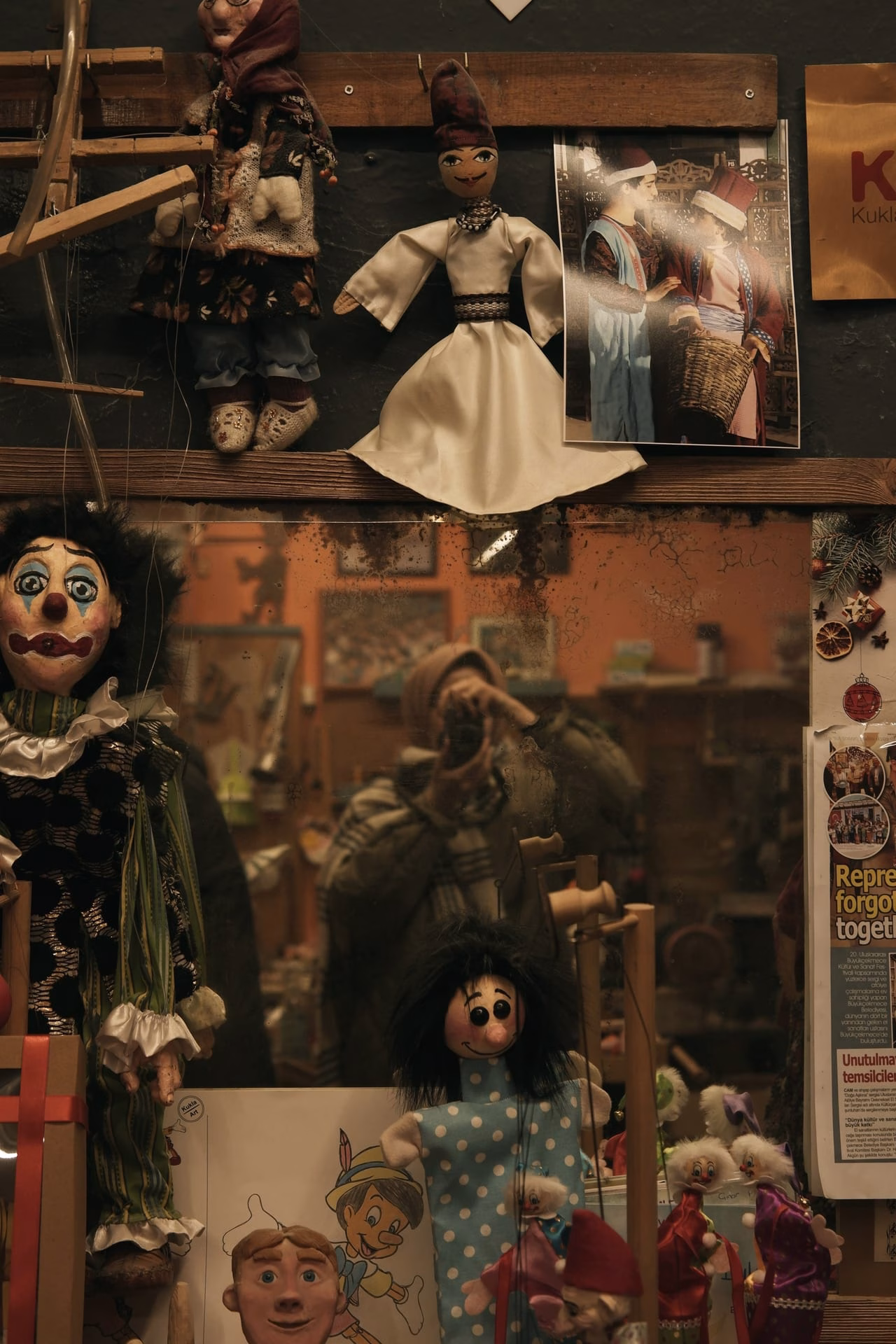 A vintage shop mirror reflects a quirky display of dolls and puppets.