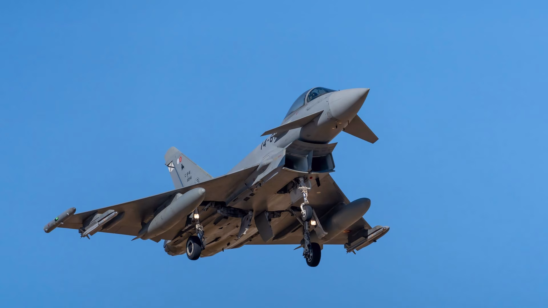 Eurofighter Typhoon jet captured mid-flight against a clear blue sky in Albacete, Spain.