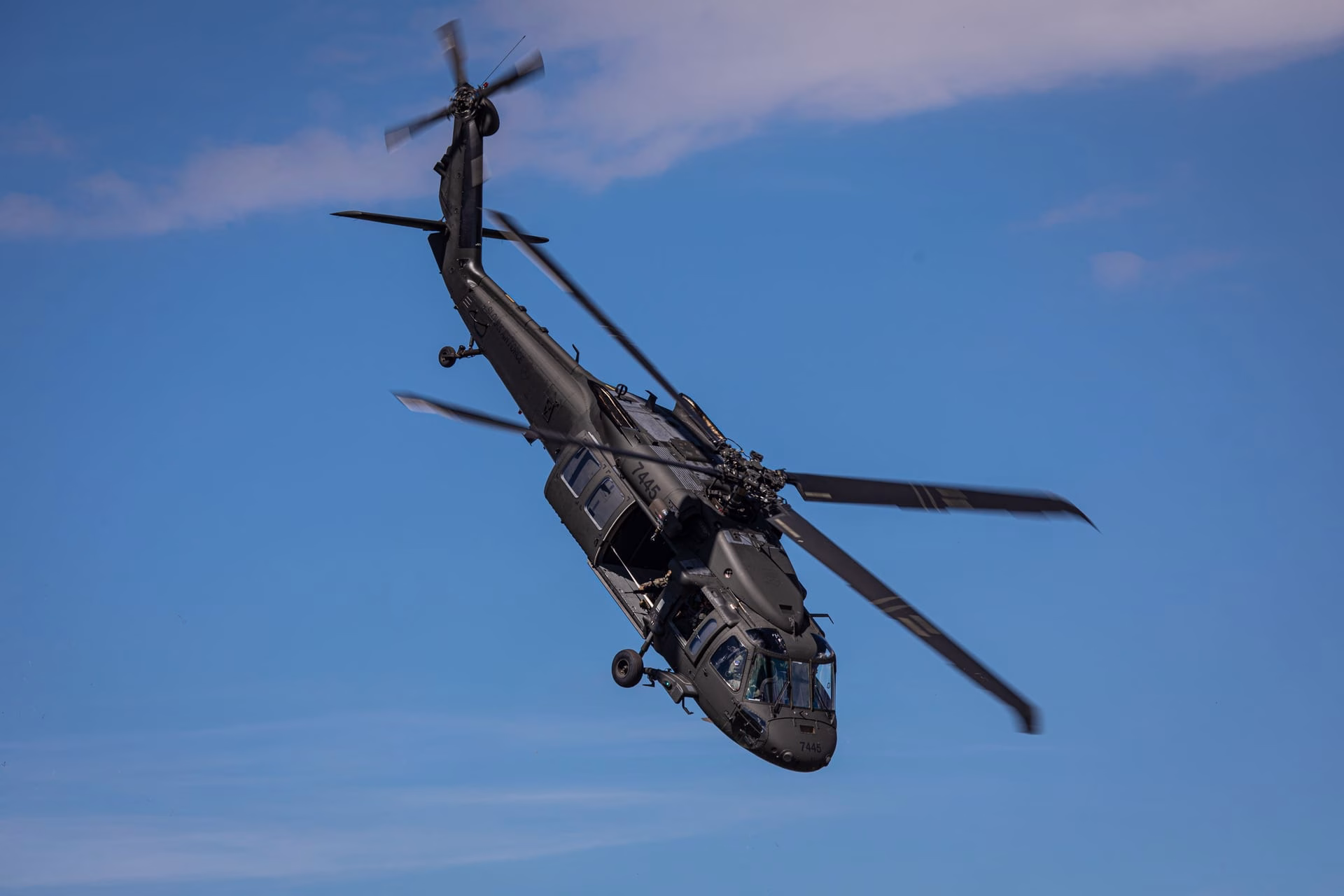 A stunning image of a UH-60 Black Hawk helicopter performing a maneuver in the clear skies of Slovakia.